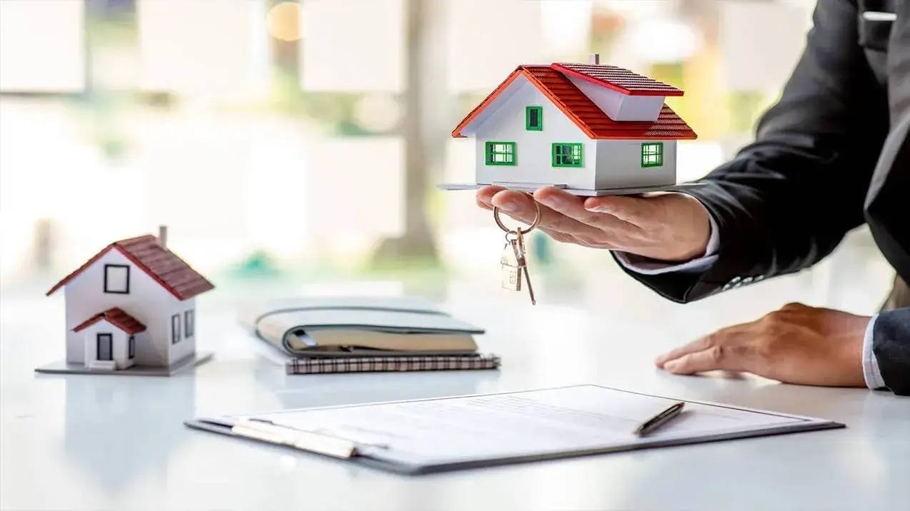 Agente profissional com modelo de casa e chaves para seu Financiamento de Imóvel de Alto Padrão ou Luxo.
