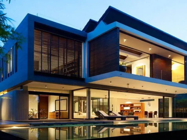 imóvel de alto padrão com arquitetura moderna em vidro e madeira, piscina de borda infinita e vegetação exuberante.