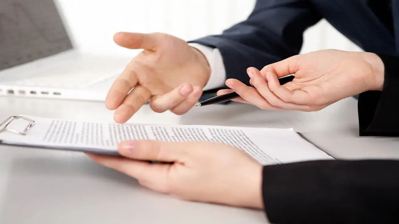 Homem aponta para contrato e mulher questiona com caneta na mão sobre como funciona um contrato de exclusividade.