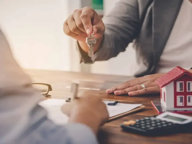Homem entrega a chave do imóvel a uma mulher feliz. A celebração de um contratodeexclusividadeimobiliaria.