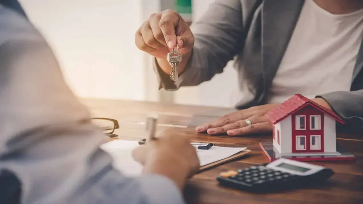 Homem entrega a chave do imóvel a uma mulher feliz. A celebração de um contratodeexclusividadeimobiliaria.
