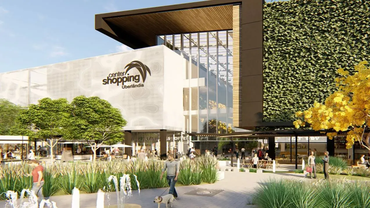 Fachada contemporânea do Center Shopping Uberlândia, com parede verde vertical e pessoas passeando na área externa.