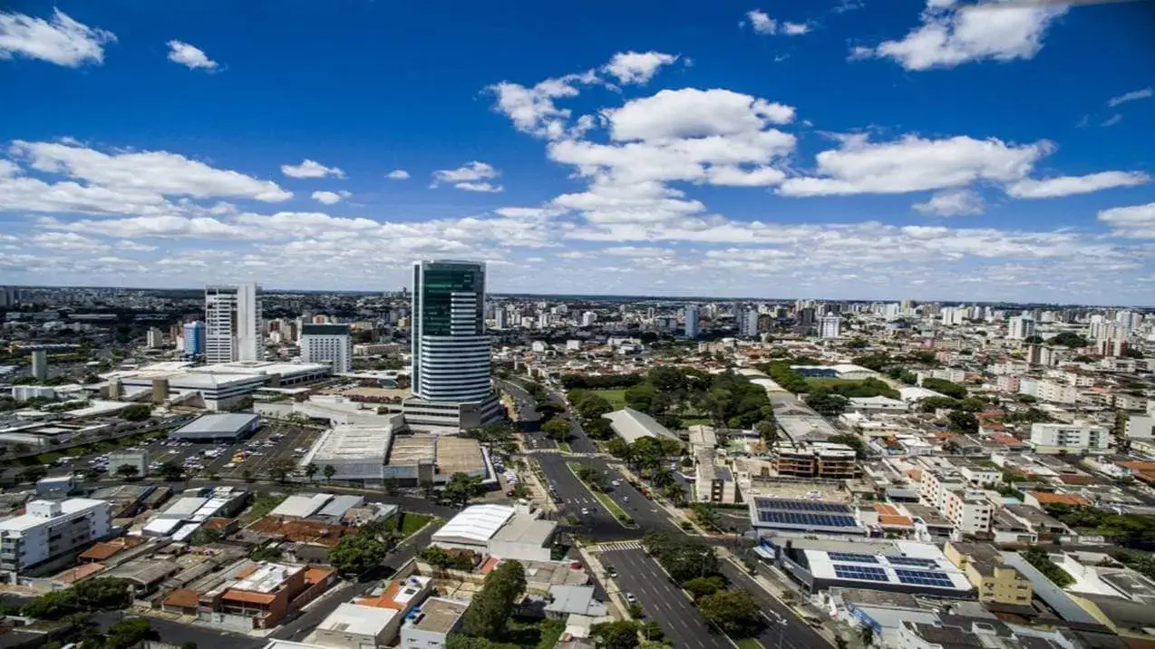 Vista aérea da paisagem urbana do bairro Santa Mônica em Uberlândia, Minas Gerais, com prédios, árvores e dois arranha-céus.