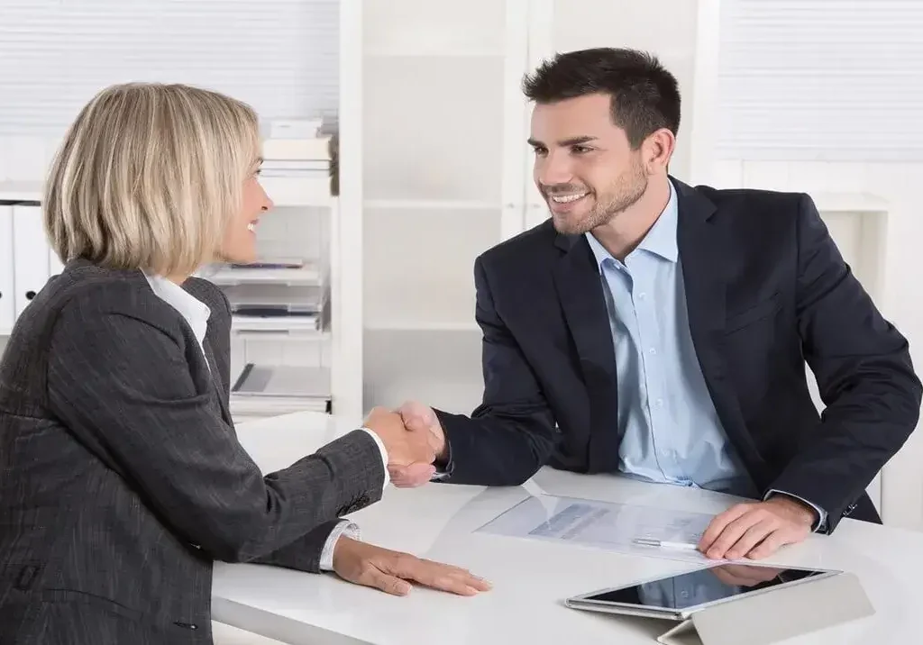 Corretora e cliente selam acordo com aperto de mãos, gerando confiança para a fidelização de proprietário de imóveis.