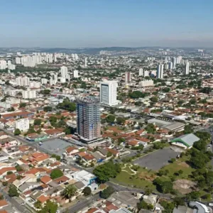 Vista aérea de Jardim América, Goiânia. Casas baixas e arborizadas contrastam com prédios altos sob um céu azul e ensolarado.
