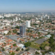 Vista aérea de Jardim América, Goiânia. Casas baixas e arborizadas contrastam com prédios altos sob um céu azul e ensolarado.